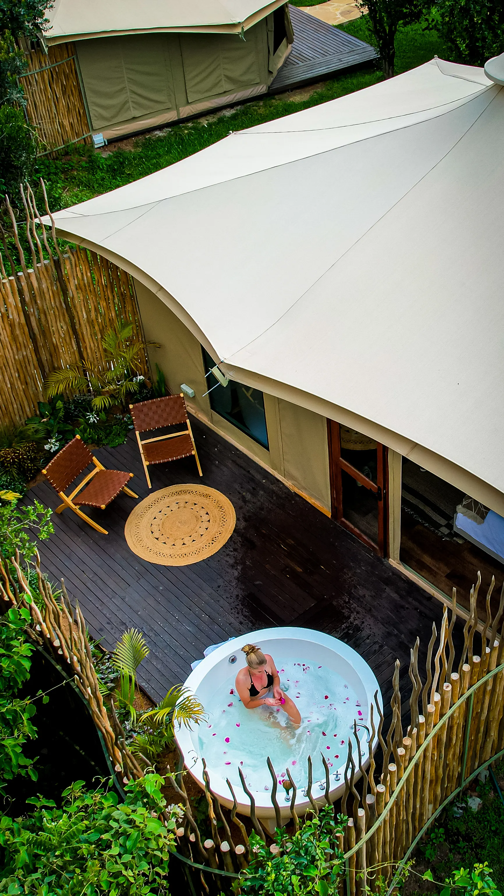 Aerial view of a tented suite deck with a private outdoor soaking tub among the trees