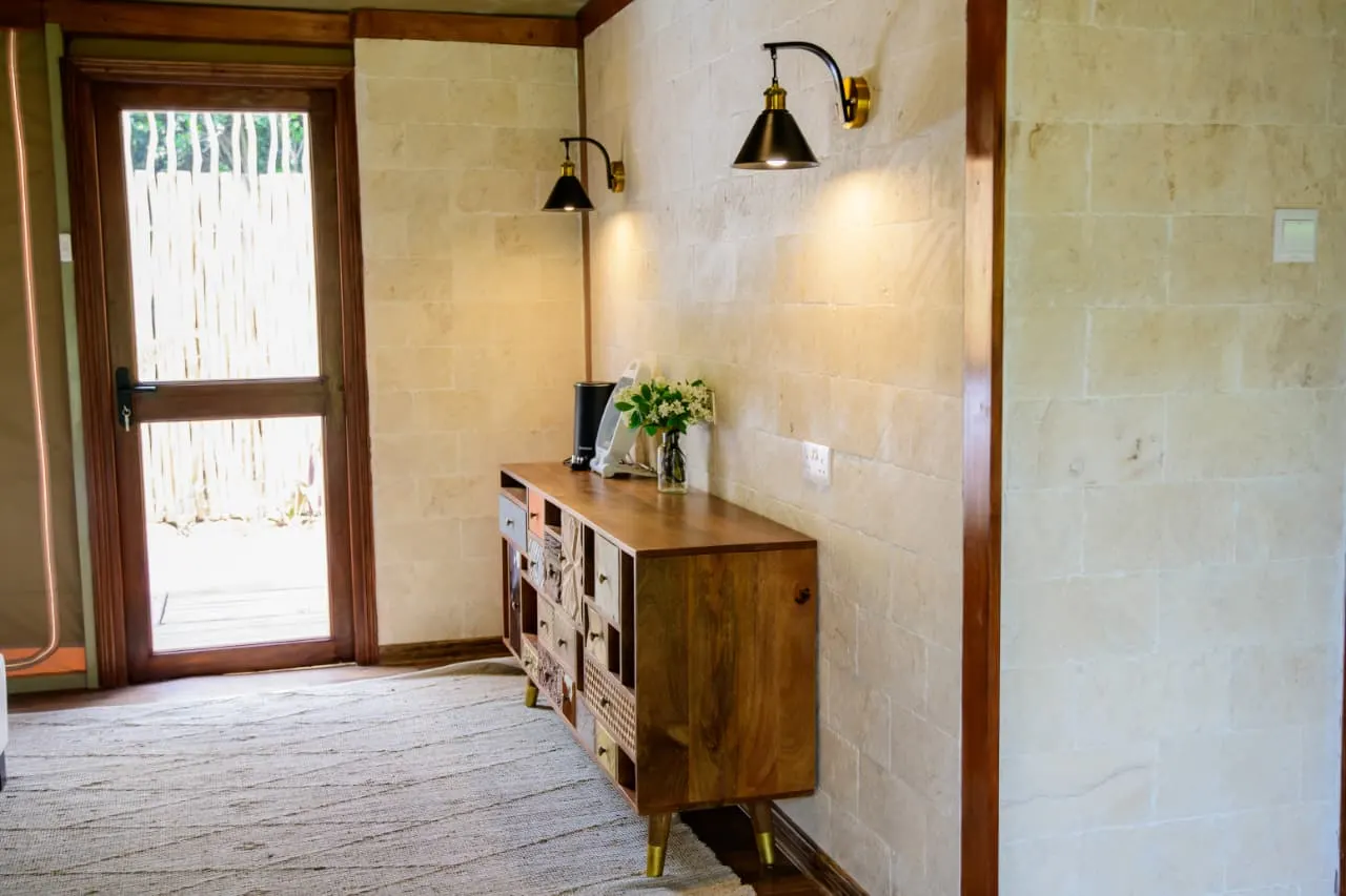 A tented suite entrance with a timber dresser and brass wall lamps
