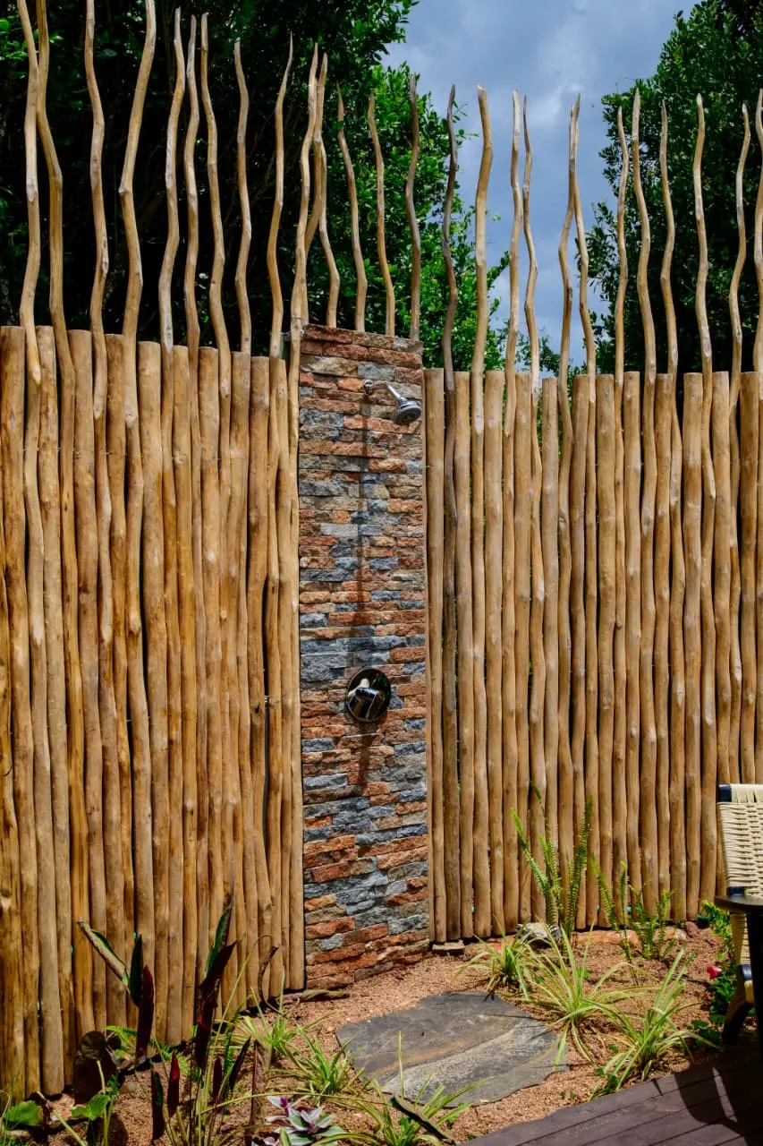 An open-air stone rainforest shower behind a timber screen at a Mtalii tented suite
